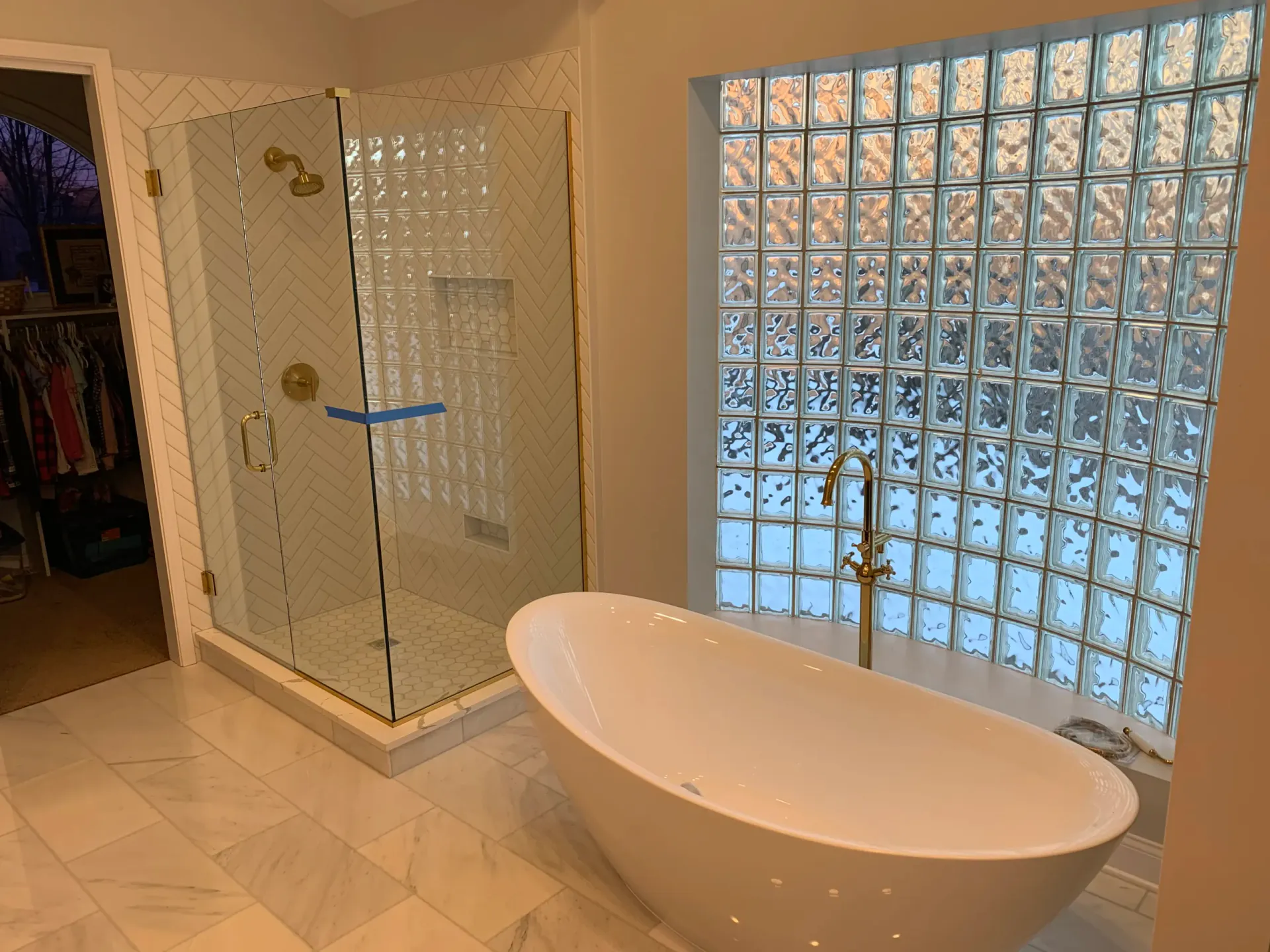 Bathroom with soaking tub, herringbone tile, and glass-block window