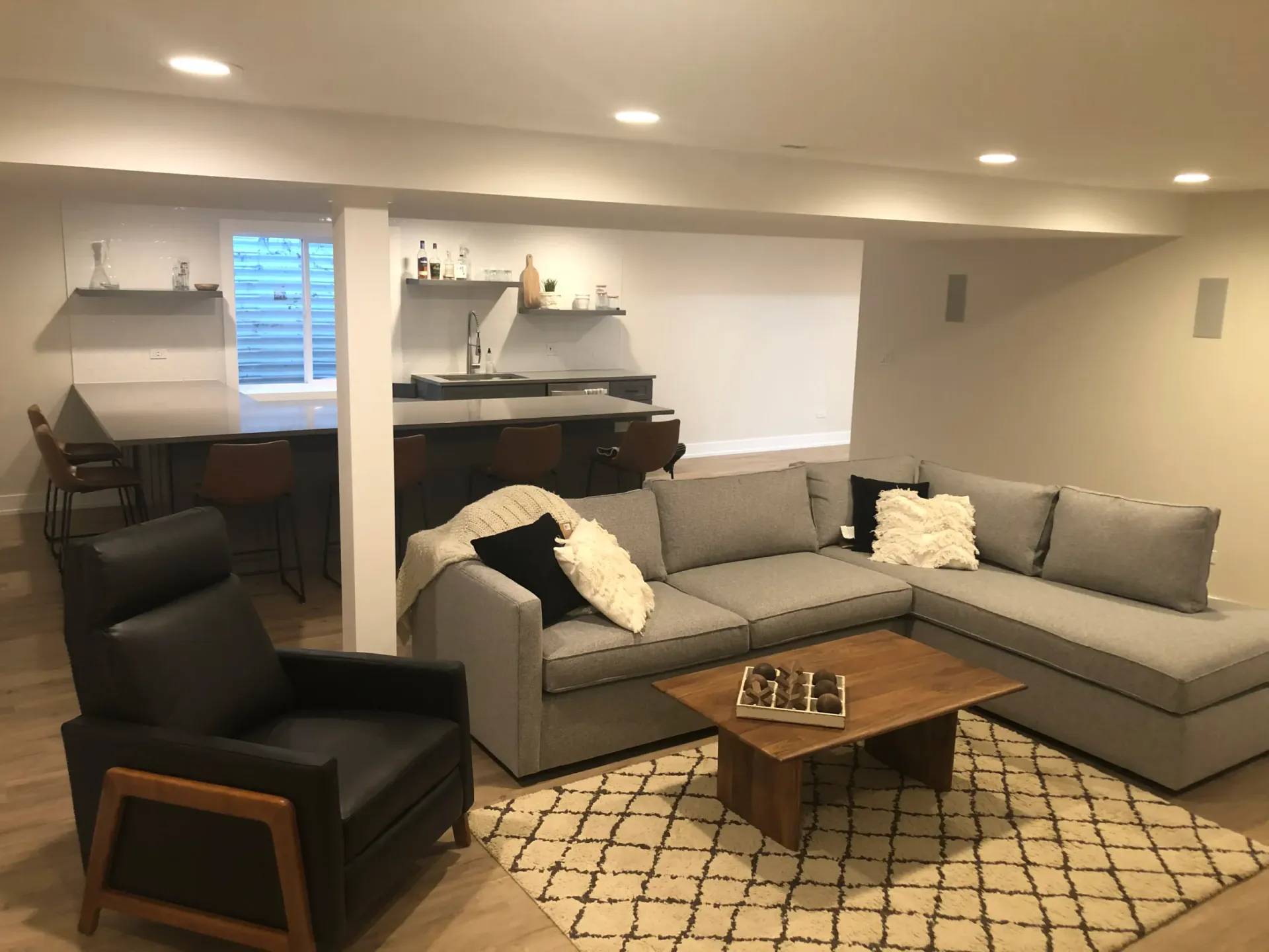 Finished lower-level lounge with a wood-slat ceiling, a bar, pendant lights, and glass doors