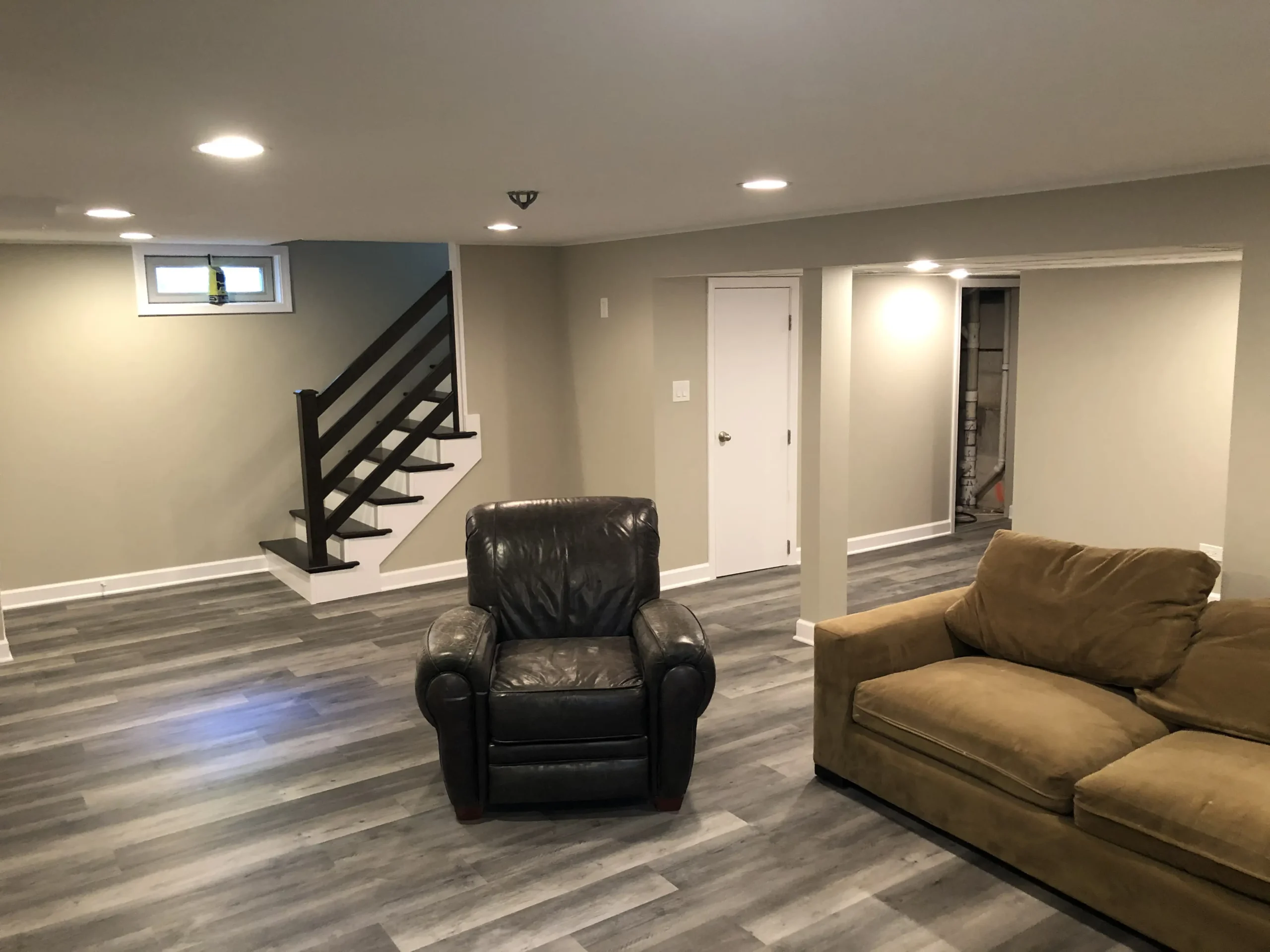 Finished basement with hardwood-look floors and dark staircase