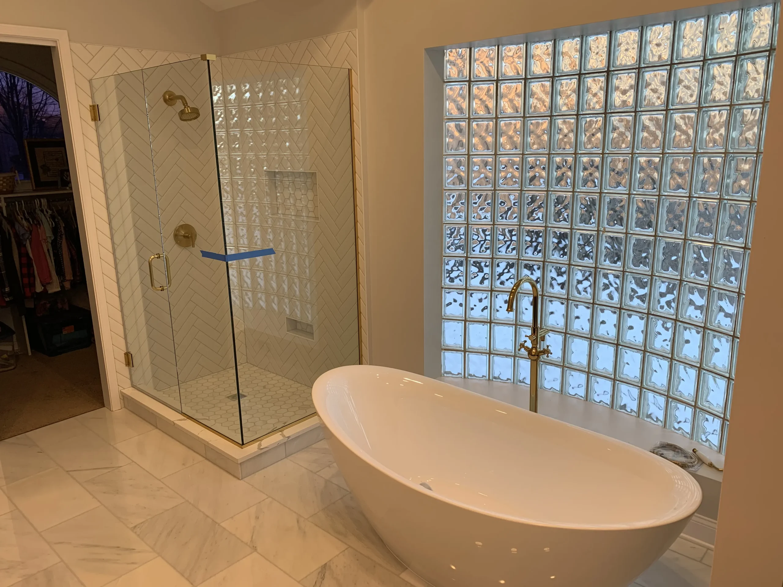 Bathroom with soaking tub, herringbone tile, and glass-block window